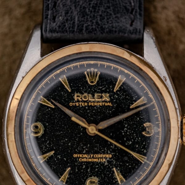 Close-up of a Rolex Oyster Perpetual "Big Bubble Back" Ref. 6107 Black Dial, featuring a black leather strap and gold accents.