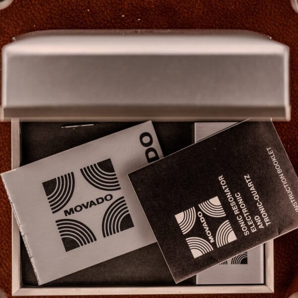 Two Movado booklets inside an open watch box highlight the Movado / Zenith Electronic Tuning Fork Cal ESA 1962, showcasing its box and papers.