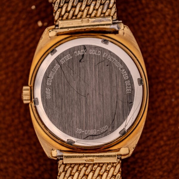 Movado / Zenith Electronic Tuning Fork Cal ESA 1962 wristwatch with a gold case, scratched stainless steel back engraved with specs and Tuning Fork logo, shown on a brown surface. Comes with box and papers.