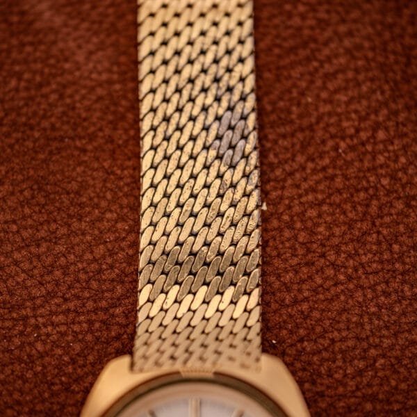 Close-up of the Movado/Zenith Electronic Tuning Fork Cal ESA 1962 gold band with a textured interlocking pattern on brown leather, evoking classic elegance; includes original box and papers.