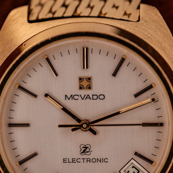 Close-up of a gold Movado / Zenith Electronic Tuning Fork Cal ESA 1962 wristwatch showing 9:14, with “Electronic Tuning Fork” on the dial. Comes with box and papers.