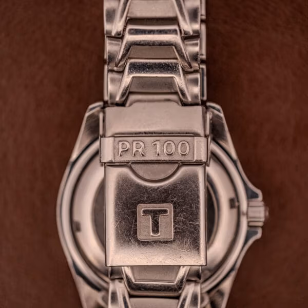 Clasp blade of the Tissot PR100 stamped PR 100 with the large Tissot T-logo recessed into the deployant face.