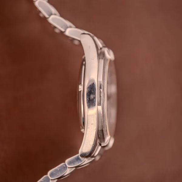 Side profile of the Tissot PR100 showing the integrated lug-to-bracelet transition and the smooth polished case flank.