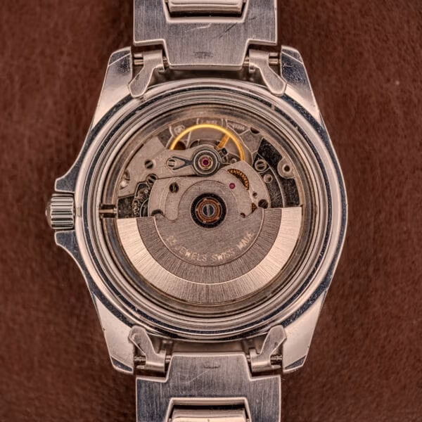 Movement view of the Tissot PR100 day-date with the signed automatic rotor reading JEWELS SWISS MADE across its arc.