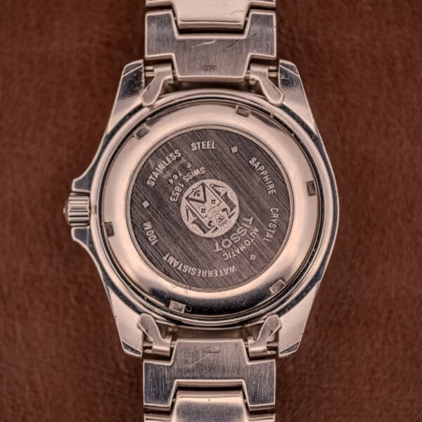 Caseback of the Tissot PR100 engraved STAINLESS STEEL SAPPHIRE CRYSTAL TISSOT AUTOMATIC WATERRESISTANT 100M around the central Tissot crest.