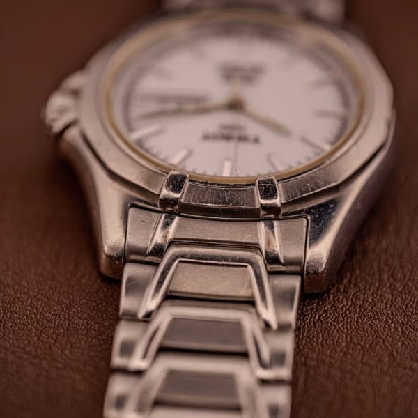 Bracelet detail of the Tissot PR100 showing the H-link construction with brushed outer links and polished center bevel running into the case.