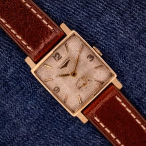 Vintage Longines square in 10K gold filled on brown leather strap shown dial-up at angle against denim backdrop
