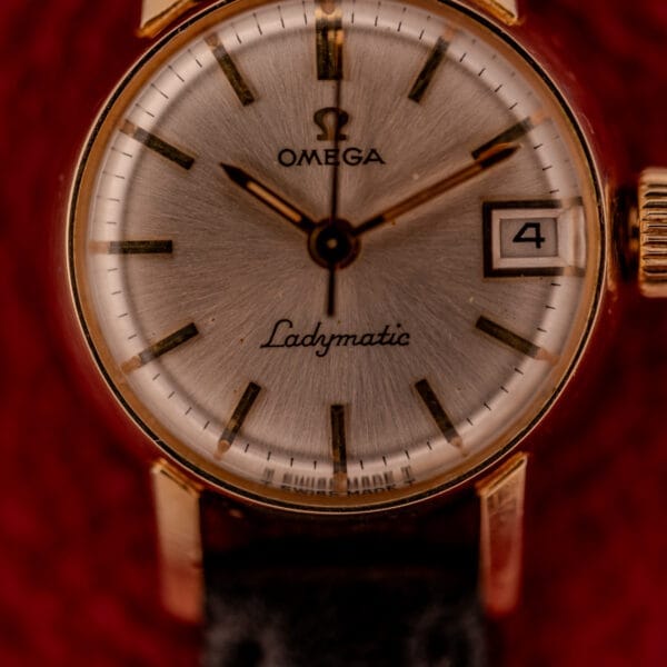 Close-up of the Omega Ladymatic Sunburst Dial Ref. W 5294, featuring a gold case, sunburst dial, date display at 4 o'clock, and powered by the Cal. 680 movement.