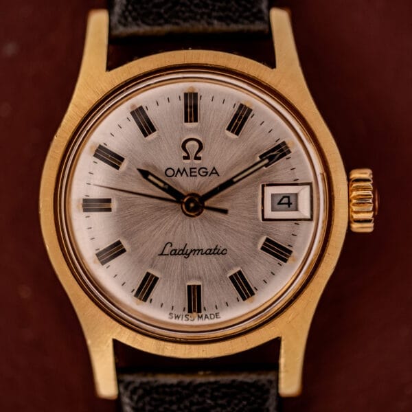 Omega Ladymatic Sunburst Dial Ref. MD 566.021 with Cal. 680 movement, sunburst dial, date window, and black leather strap.