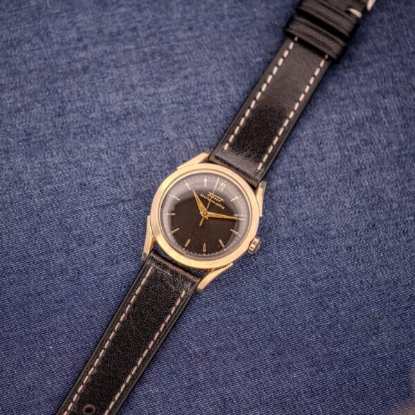 The Tissot Automatic Bumper with a black dial and gold filled case (Cal. 28.5T) is displayed on a blue denim background.