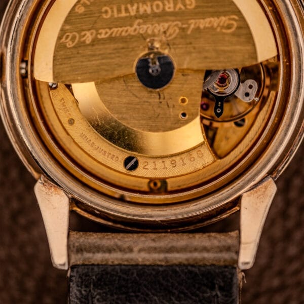 Close-up of a Girard Perregaux Gyromatic Ref. B-1852 Automatic Cal. 21 vintage watch’s gold movement and serial number inside the caseback, shown with a leather strap.