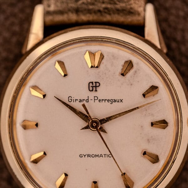 Close-up of a vintage Girard Perregaux Gyromatic Ref. B-1852 wristwatch, showcasing gold markers, hands, and the iconic Automatic Cal. 21 movement.