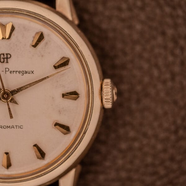 Close-up of a vintage gold Girard Perregaux Gyromatic Ref. B-1852 wristwatch featuring a white face, gold hour markers, and the renowned Automatic Cal. 21 movement.