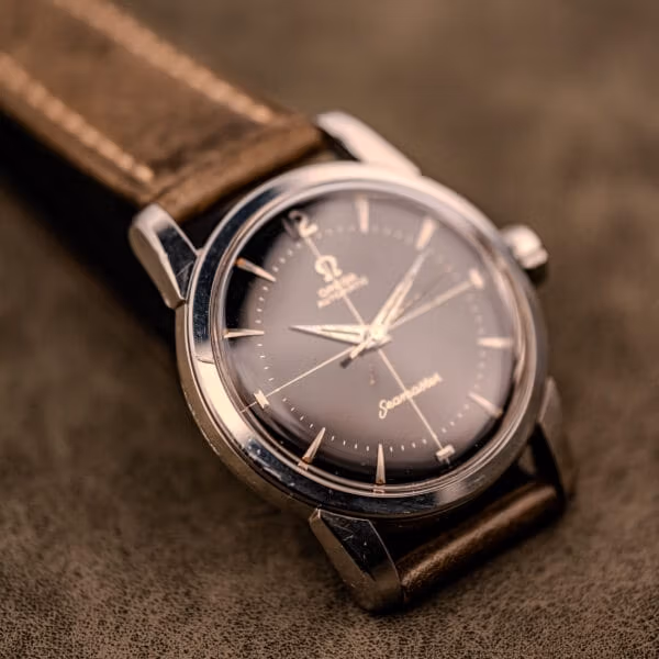 Vintage Omega Seamaster Ref. 2848 black dial watch with the original signed Omega crown shown against a brown suede backdrop