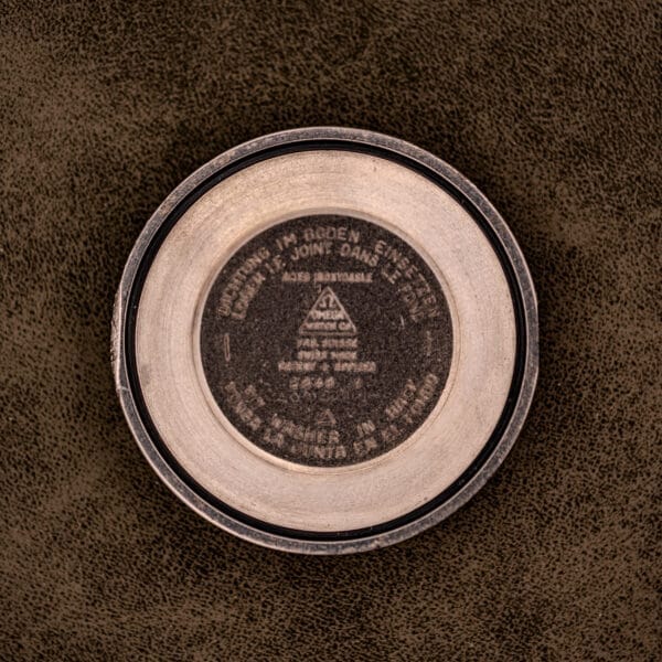 An Omega Automatic Seamaster Ref. 2848 Black Dial Cal. 500, featuring a round metal case with a black dial and dark central engraving, is displayed on a textured brown surface.