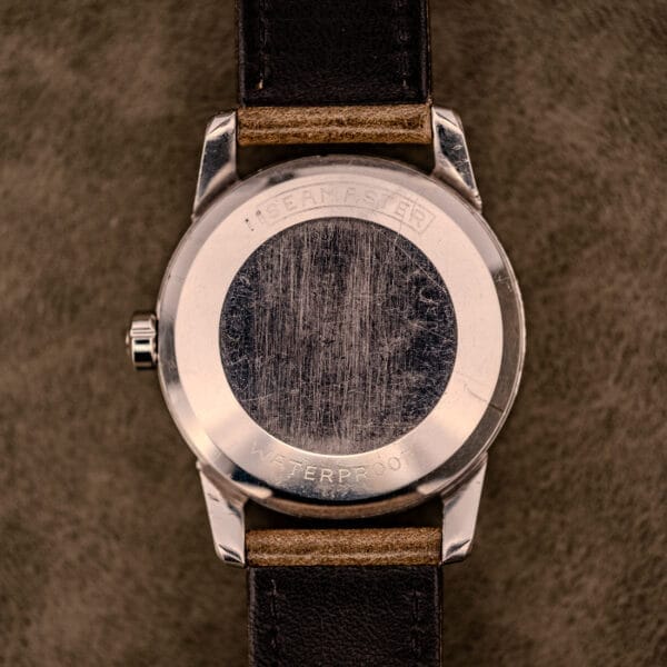 The scratched back of an Omega Automatic Seamaster Ref. 2848 Black Dial Cal. 500 with a black leather strap lies on a brown surface.