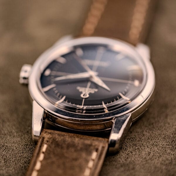 A close-up of an Omega Automatic Seamaster Ref. 2848 with a black dial, Cal. 500 movement, and brown leather strap, resting on a soft, textured surface.