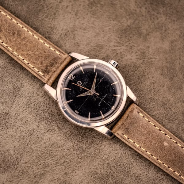 Overhead view of the vintage Omega Seamaster Ref. 2848 black dial automatic on textured grey suede with olive leather strap