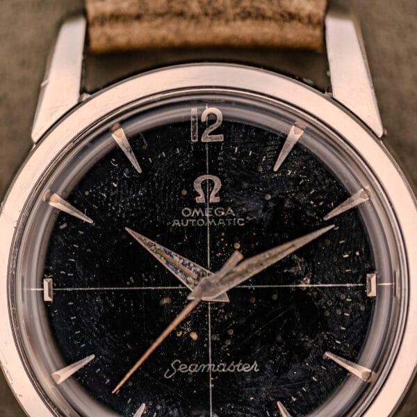 Close-up of an Omega Automatic Seamaster Ref. 2848 watch, featuring a black dial (Cal. 500) with visible wear and scratches.