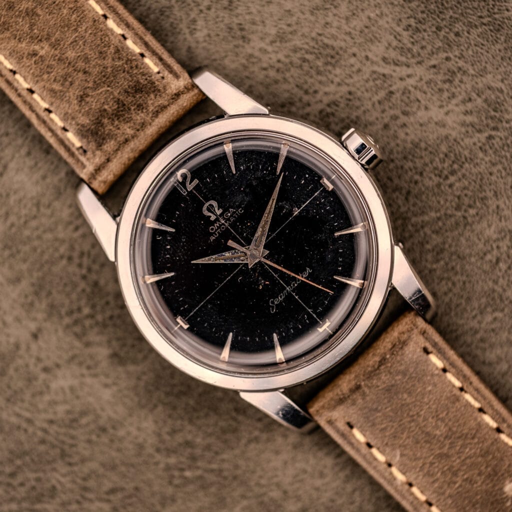 An Omega Automatic Seamaster Ref. 2848 with a black dial and brown leather strap, Cal. 500, displayed on a suede surface.