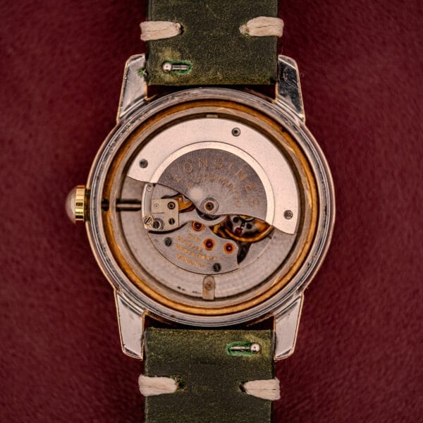 Back view of the Longines Automatic Conquest Ref. 9000-1 with a 14k gold capped case, featuring its exposed mechanical movement and green leather strap.
