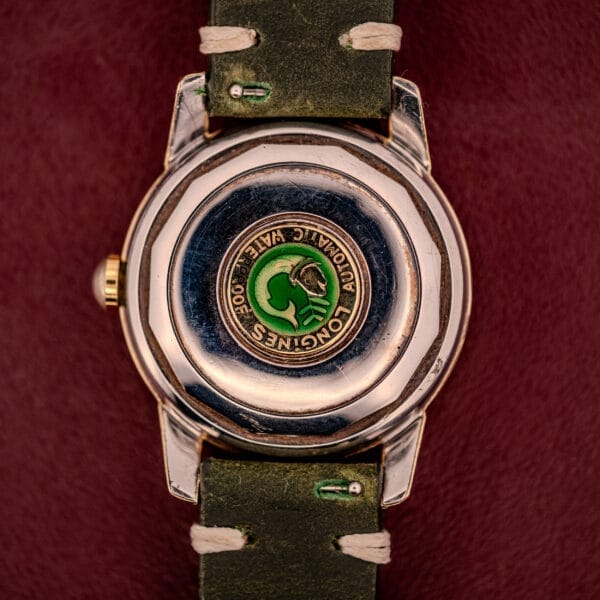 Close-up of the Longines Automatic Conquest Ref. 9000-1 14k Gold Capped Case watch back, featuring "Water 300," a green emblem, and a leather strap.