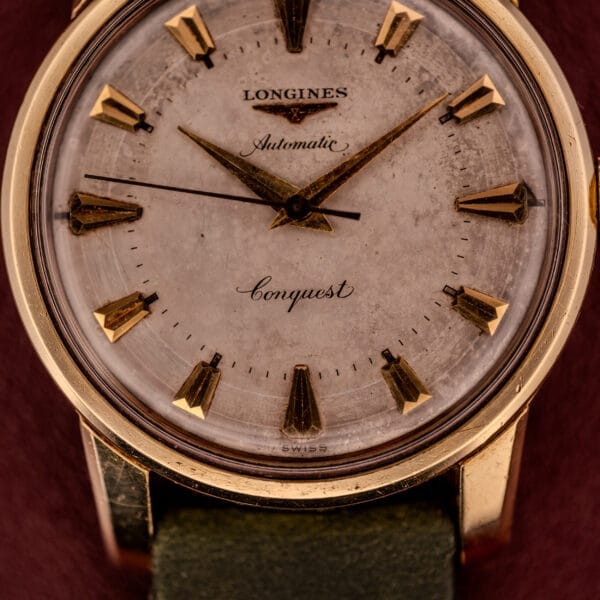 Close-up of a Longines Automatic Conquest Ref. 9000-1 with a 14k gold capped case, gold markers, and stylish green strap.