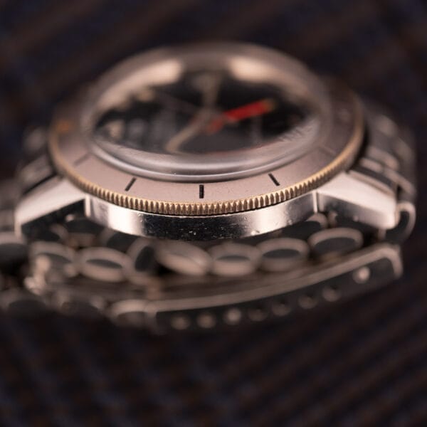 Close-up of a Zodiac Aerospace GMT Ref. 752-934 Black Dial & Chrome Bezel wristwatch with a bold red hand, displayed at an angle on a dark textured surface.