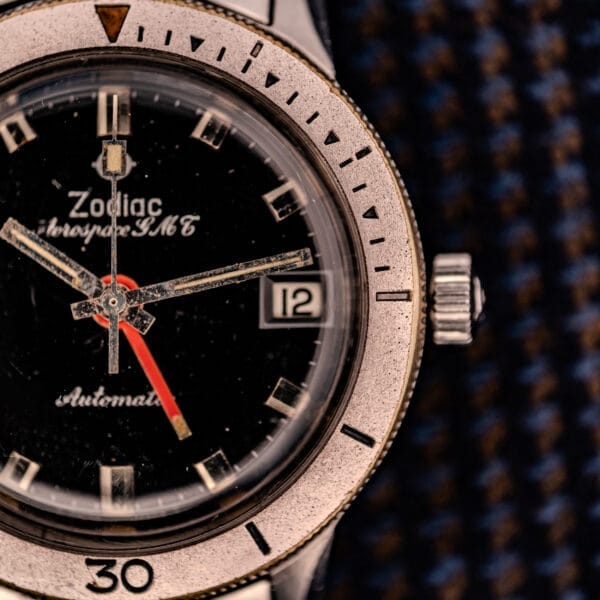 Close-up of a Zodiac Aerospace GMT Ref. 752-934 wristwatch featuring a black dial and chrome bezel, showing the time at 8:22 and the date as the 12th.