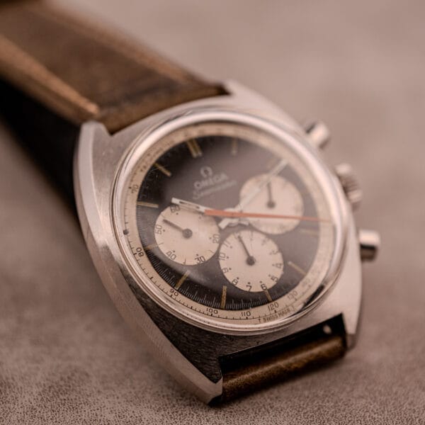 Close-up of an Omega Seamaster Chronograph Ref. 145.016 with a reverse panda dial and leather strap, elegantly displayed on a gray surface.