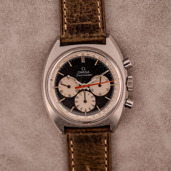Omega Seamaster Chronograph Ref. 145.016 with a reverse panda black and white dial, brown leather strap, and distinctive red-tipped second hand.