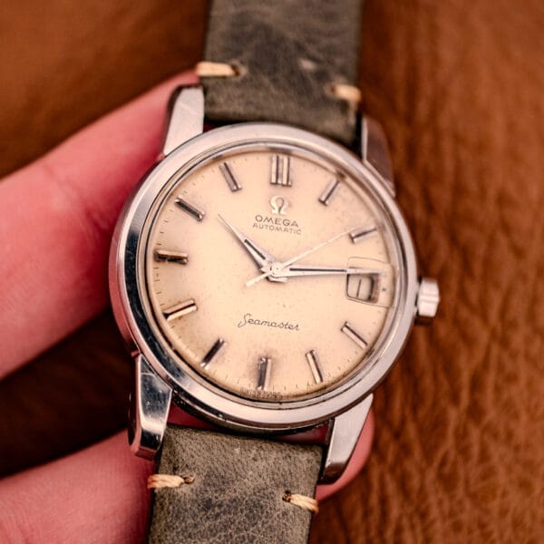 A close-up of an Omega Automatic Seamaster Ref. 2849 with chunky lugs, featuring a worn leather strap and cream dial in a classic stainless steel case.