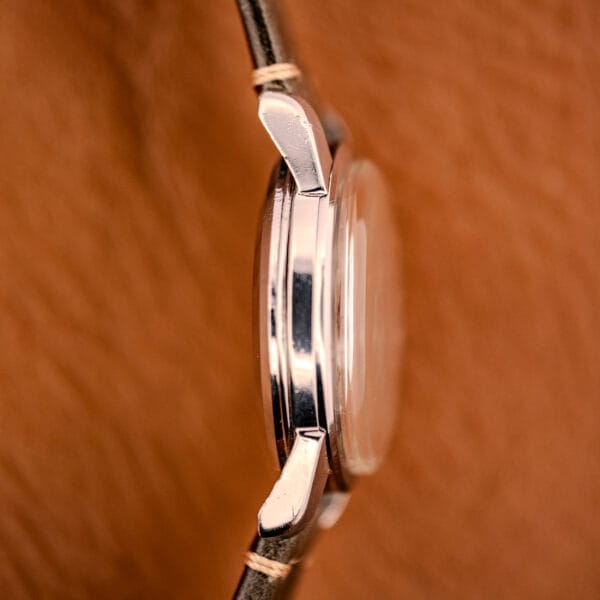 Close-up side view of the Omega Automatic Seamaster Ref. 2849 stainless steel chunky lugs case with a leather strap, set against a brown textured background.