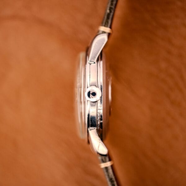 Side view of an Omega Automatic Seamaster Ref. 2849 with chunky lugs, leather strap, and stainless steel crown, set against a brown textured background.