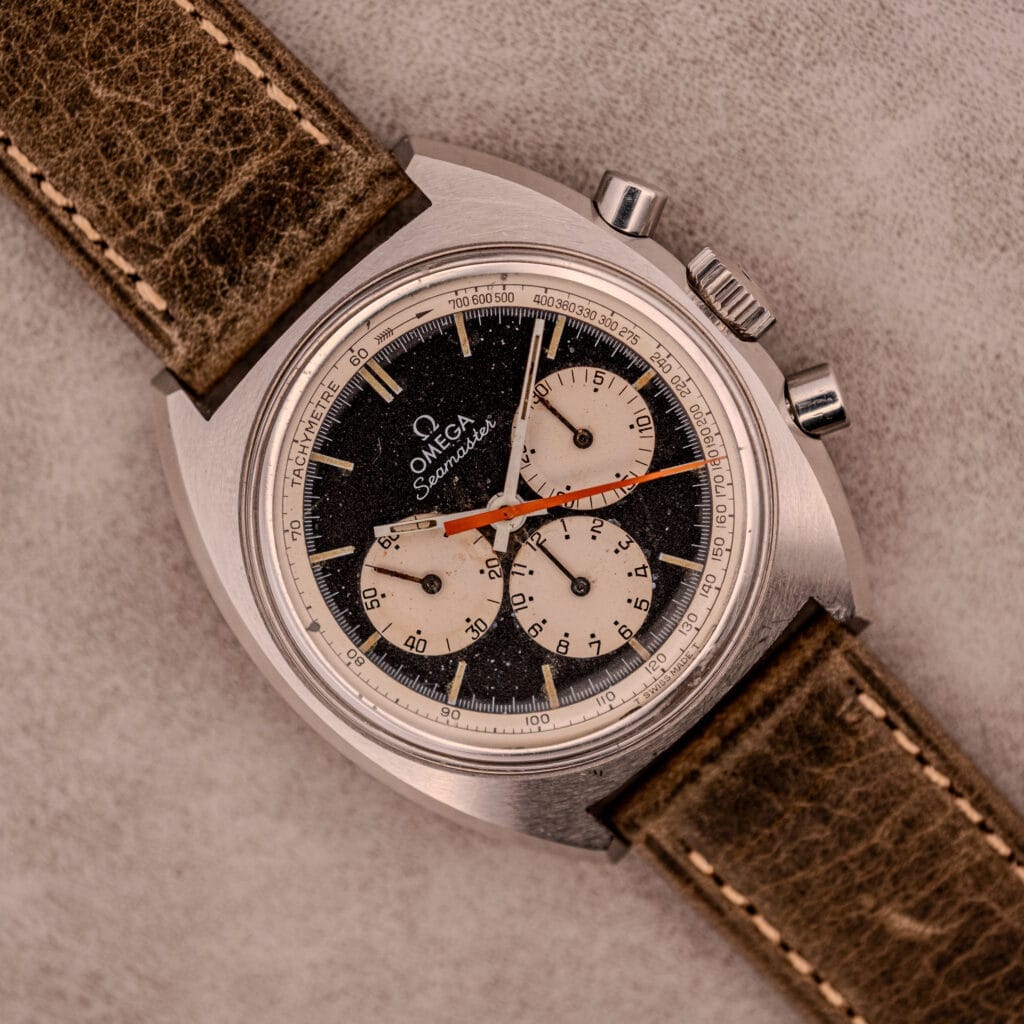 Omega Seamaster Chronograph Ref. 145.016 with reverse panda dial, shown on a brown leather strap and elegantly displayed on a light textured surface.