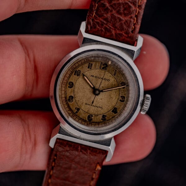 A close-up of the Movado "Acvatic" FB Case Sector Dial Ref. 11730 Cal. 150MN wristwatch with a brown leather strap, aged yellow dial, and classic sector dial design.