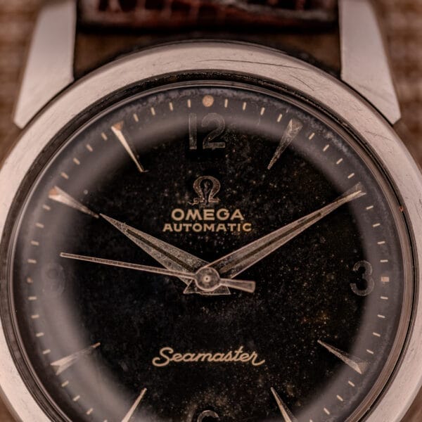 Close-up of a 1956 Omega Seamaster Automatic Ref. 2828-6 SC Cal. 470 in stainless steel, showcasing its black dial and silver hands.