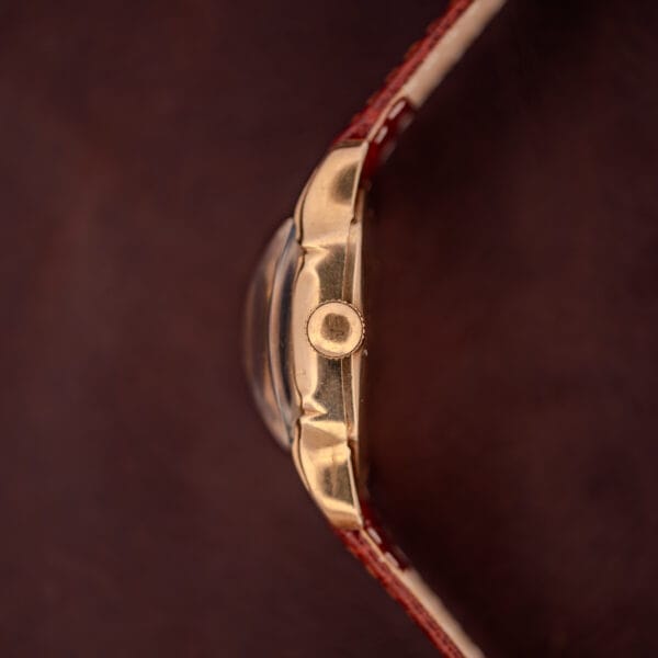 Close-up side view of the Hamilton Lawton Art Deco Gold Filled Case Manual Wind Cal. 747 wristwatch with a gold filled case and brown leather strap, set against a dark brown background.