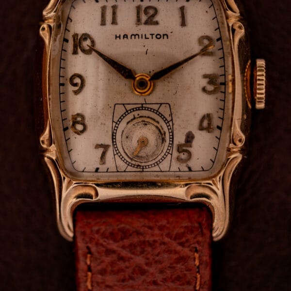 Close-up of a vintage Hamilton Lawton Art Deco Gold Filled Case wristwatch, featuring a manual wind Cal. 747 movement, worn face, and brown leather strap.