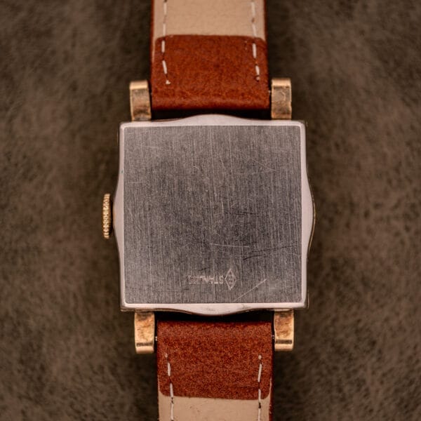 A Hamilton Art Deco Square wristwatch with a gold filled case, brown leather strap, manual wind Cal. 987-F movement, and vintage styling; shown from the scratched metal back.