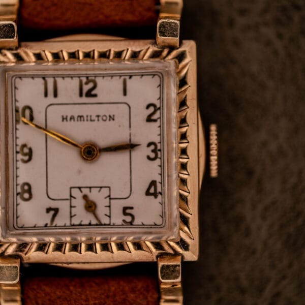 Close-up of a Hamilton Art Deco Square Gold Filled Case wristwatch, featuring manual wind Cal. 987-F movement and a brown leather strap.