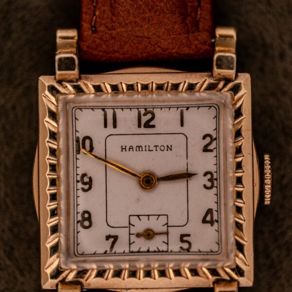 Hamilton Art Deco Square Gold Filled Case Manual Wind Cal. 987-F wristwatch featuring a white face, black numerals, and brown leather strap.