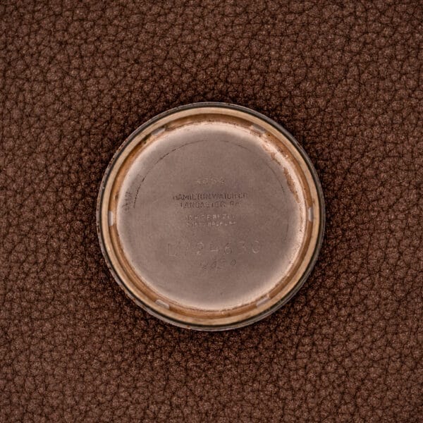 A round metal watch back engraved with "Gold Filled Case" and "Hamilton K-454 Sputnik Automatic Cal. 661," resting on a textured brown surface.