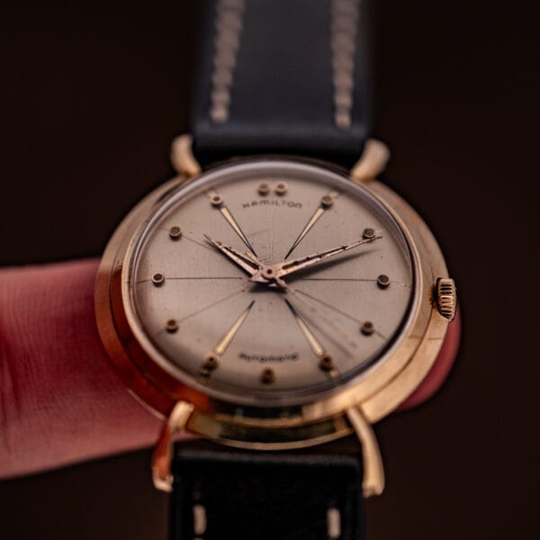 A close-up of a Hamilton K-454 Sputnik Automatic Cal. 661 wristwatch featuring a gold filled case and black leather strap.