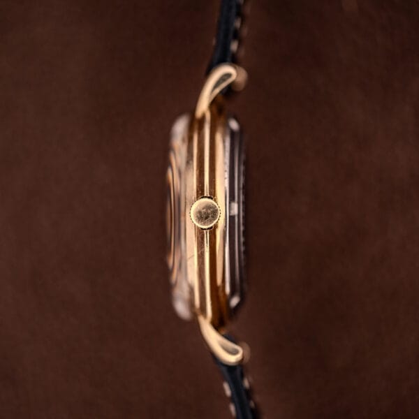 Side view of a Hamilton K-454 Sputnik Automatic Cal. 661 gold filled case wristwatch with black leather strap, shown against a brown background.