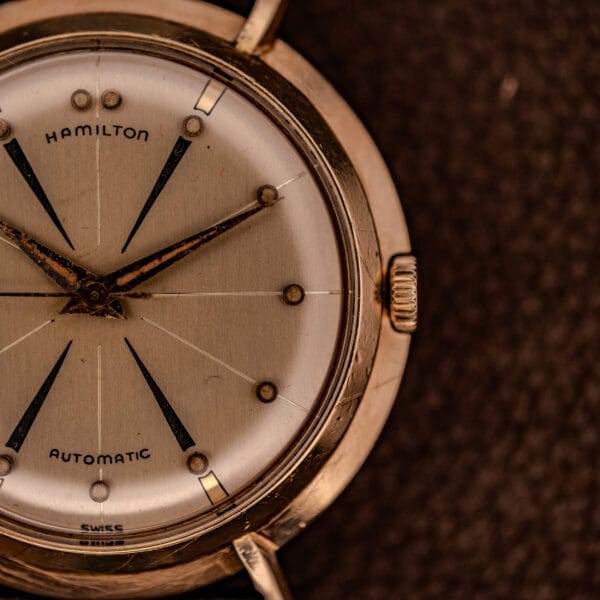 Close-up of a Hamilton K-454 Sputnik Automatic Cal. 661 with a silver dial and gold filled case, displayed on a brown surface.