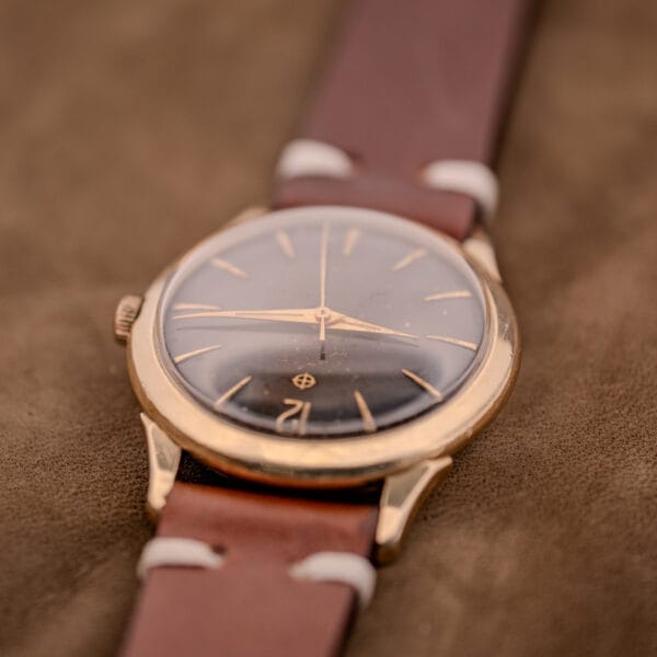 A Zodiac Hermetic Black Dial Automatic Caliber 1624 with a Gold Filled Case is elegantly displayed on a brown suede surface.