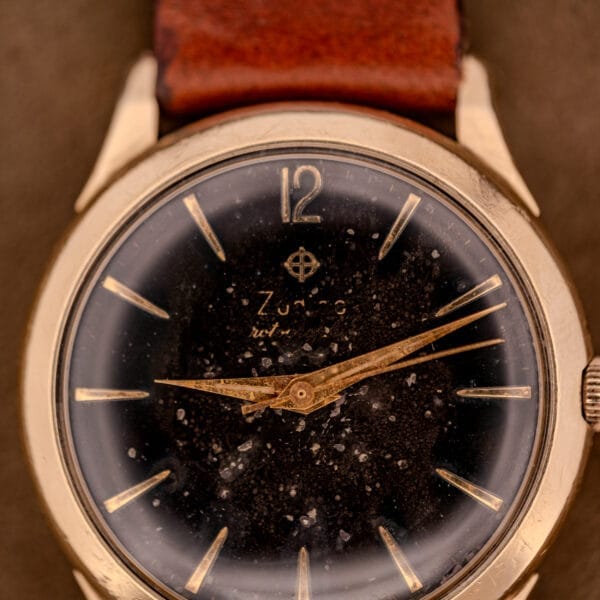 A close-up of a vintage Zodiac Hermetic Black Dial Automatic Caliber 1624 with a gold filled case and brown leather strap, featuring a worn face that shows signs of age.