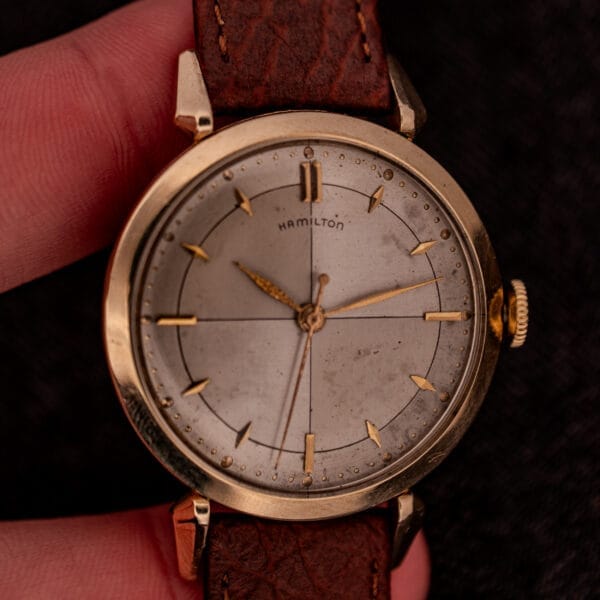 A close-up of a Hamilton Rodney Sector Dial Manual Wind watch featuring Cal. 748 movement, a 10k gold filled case, and a brown leather strap.