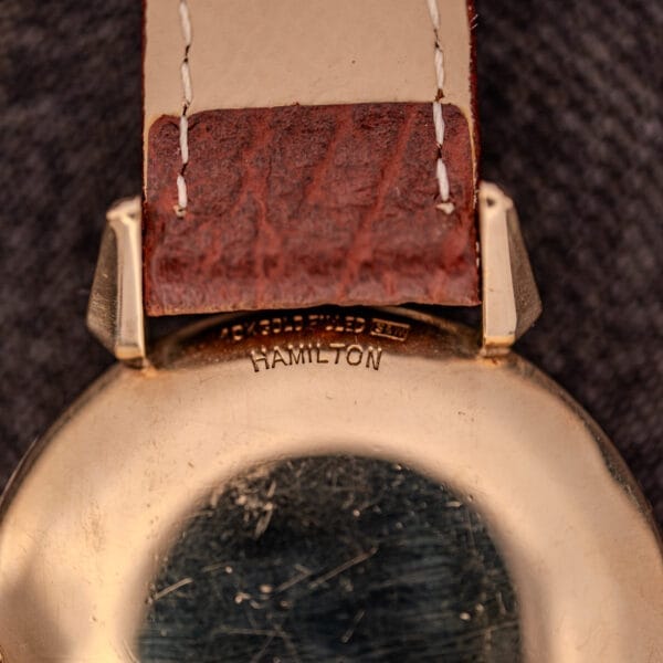 Close-up of the back of a Hamilton Rodney Sector Dial Manual Wind Cal. 748 watch, featuring a 10k gold filled case, brown leather strap with visible stitching, and manual wind movement.